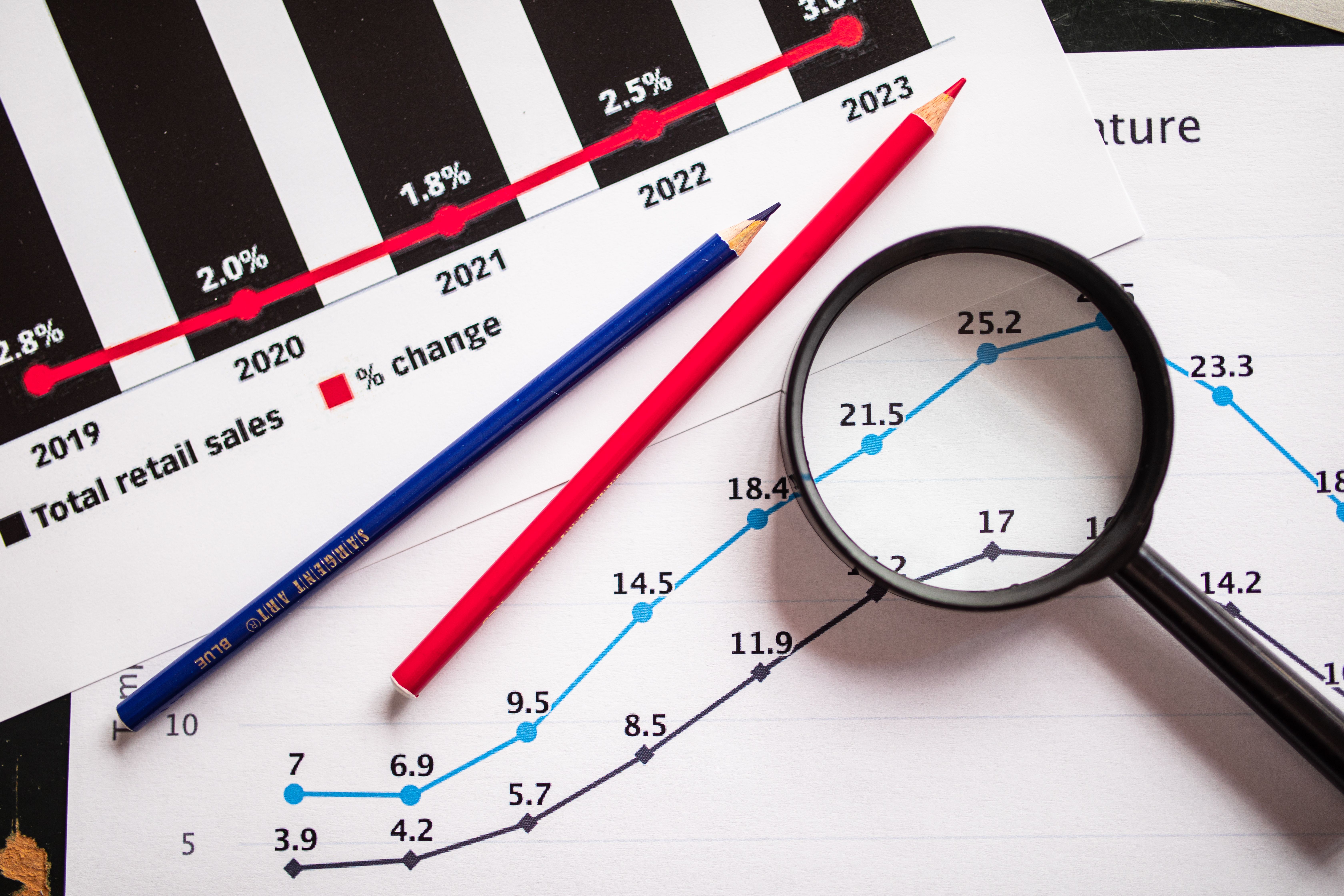 Magnifying glass and colored pencils on sales growth graphs showing long-term SEO results