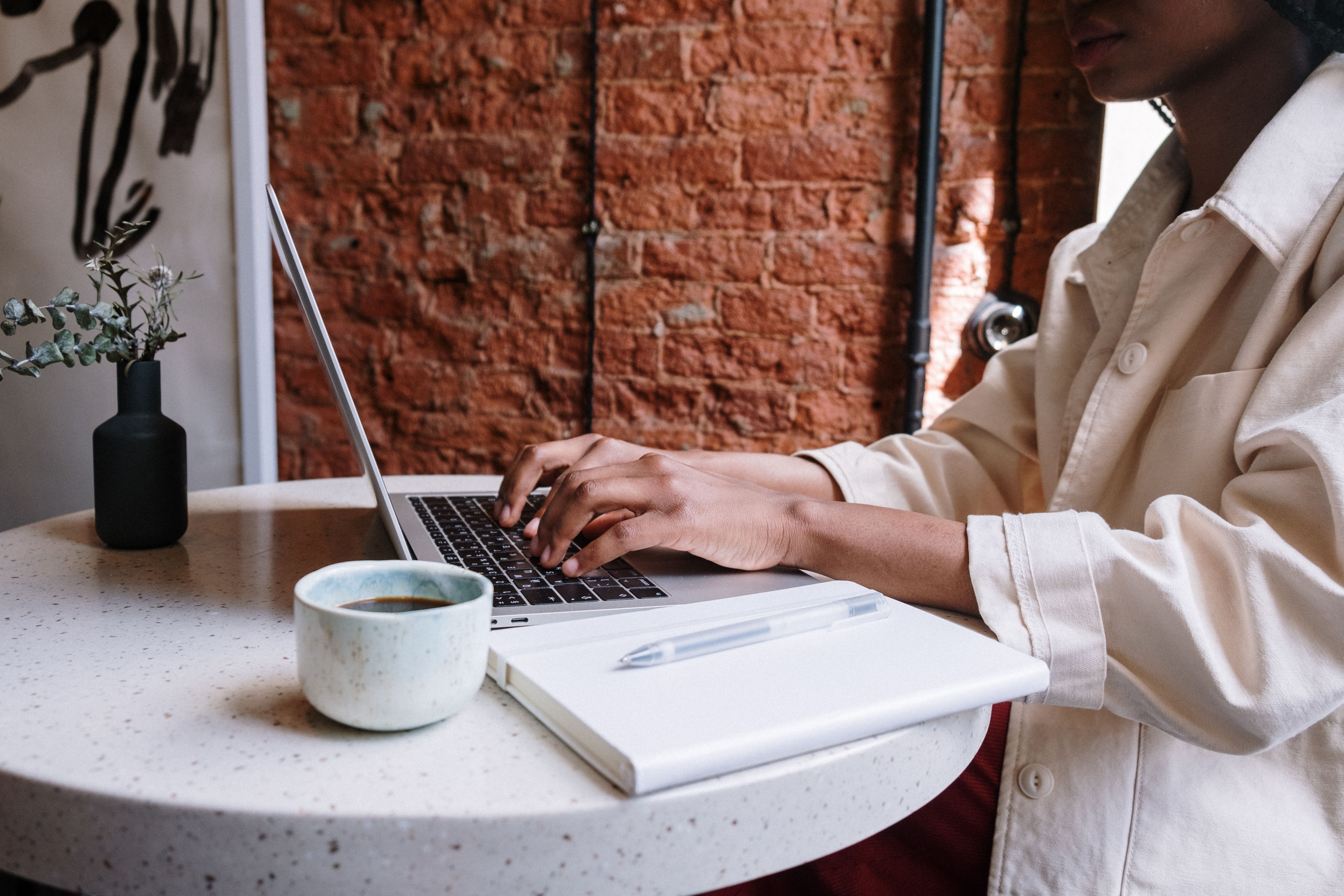 Woman writing on a laptop with coffee in a cozy cafe, representing authentic content creation